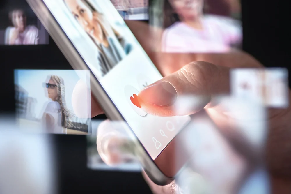 Close-up of a person using a dating app on a smartphone, tapping the heart icon on a profile photo