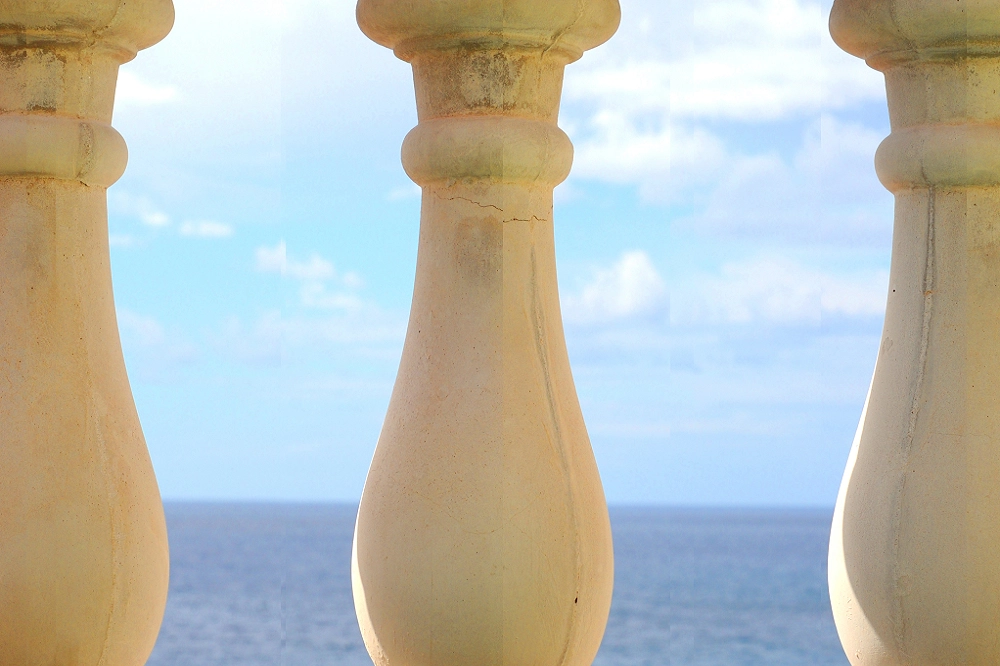 View of the ocean and sky framed between stone balusters, symbolizing peace, reflection, and open horizons